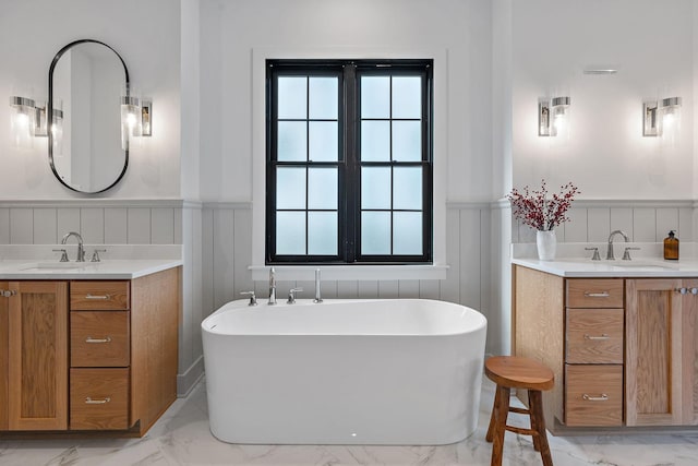 bathroom featuring marble finish floor, two vanities, wainscoting, and a sink