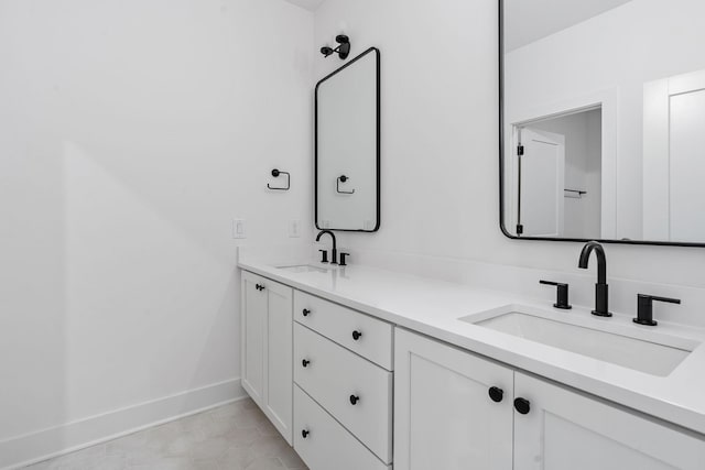 full bathroom with tile patterned flooring, a sink, baseboards, and double vanity