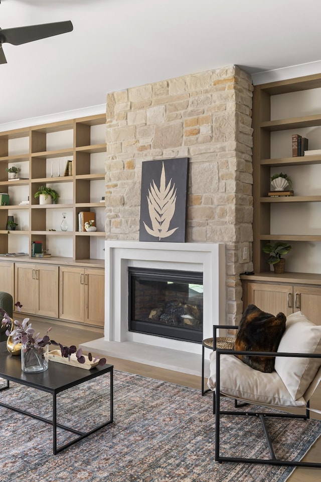 living area featuring ceiling fan and a glass covered fireplace