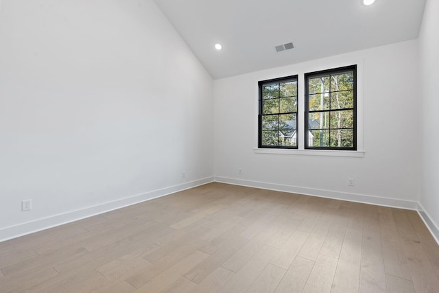 empty room featuring recessed lighting, visible vents, light wood-style floors, vaulted ceiling, and baseboards