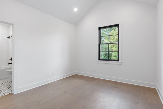 unfurnished room with lofted ceiling, recessed lighting, wood finished floors, and baseboards