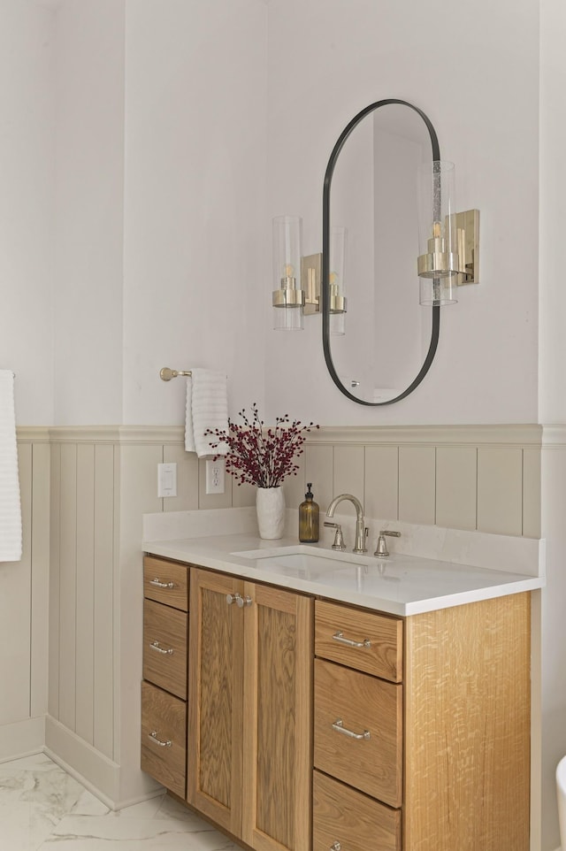 bathroom featuring marble finish floor, a wainscoted wall, and vanity