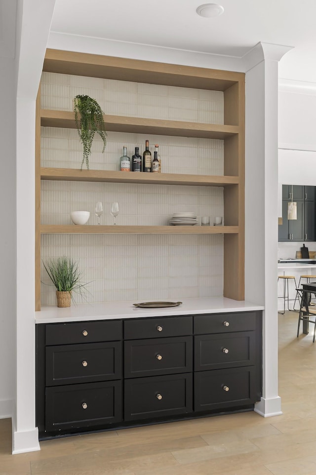 bar featuring a dry bar, light wood finished floors, and built in features