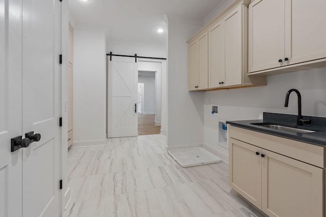 clothes washing area featuring a barn door, hookup for a washing machine, a sink, baseboards, and ornamental molding