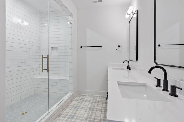 bathroom with a stall shower, visible vents, a sink, and baseboards