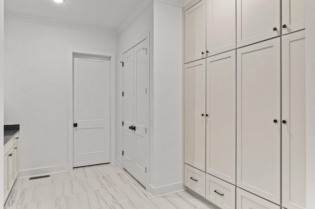 mudroom featuring ornamental molding, marble finish floor, visible vents, and baseboards