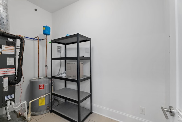 utility room featuring heating unit and electric water heater