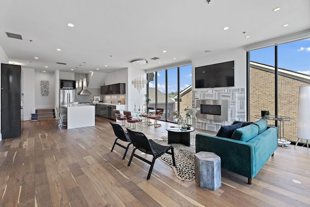 living room featuring expansive windows, light wood finished floors, visible vents, and recessed lighting