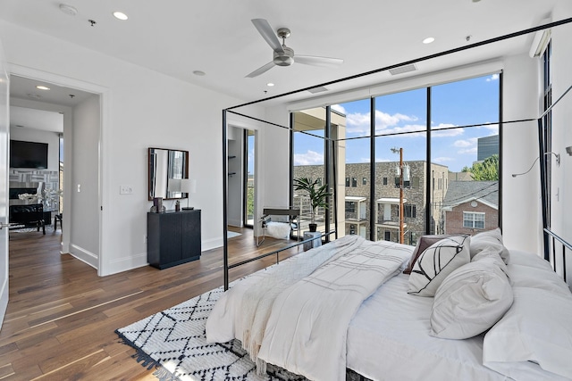 bedroom with baseboards, wood finished floors, a wall of windows, a fireplace, and recessed lighting