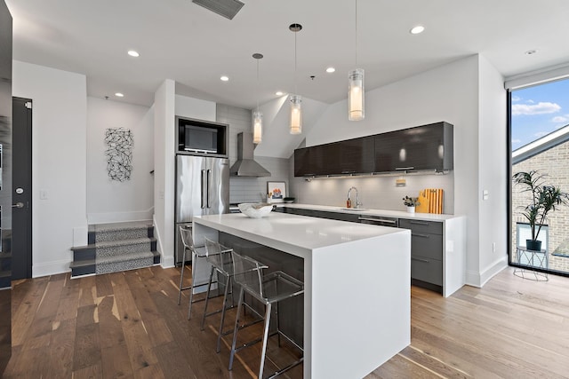 kitchen with wall chimney exhaust hood, high quality fridge, visible vents, and backsplash