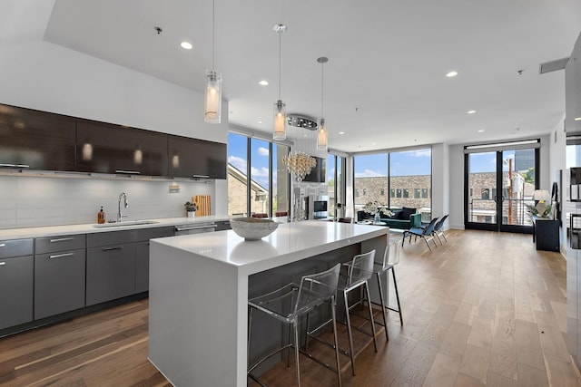 kitchen with light countertops, wood finished floors, a sink, and floor to ceiling windows