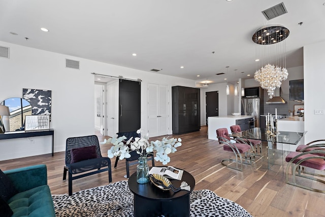 living area with wood finished floors, visible vents, and an inviting chandelier