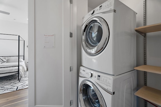 clothes washing area featuring stacked washer and dryer and wood finished floors