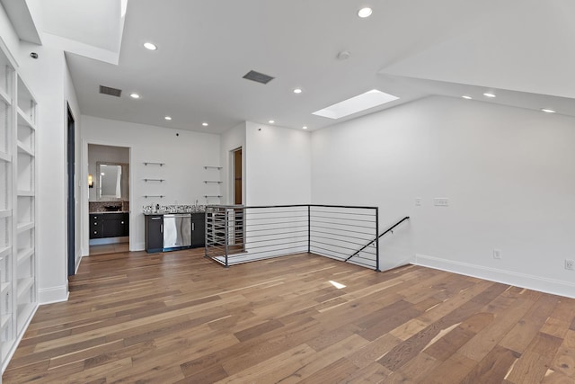 unfurnished room featuring a skylight, wood finished floors, visible vents, and recessed lighting