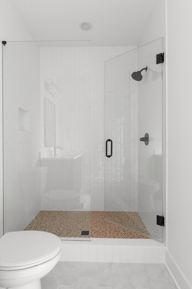 bathroom featuring toilet, a stall shower, and tile patterned flooring