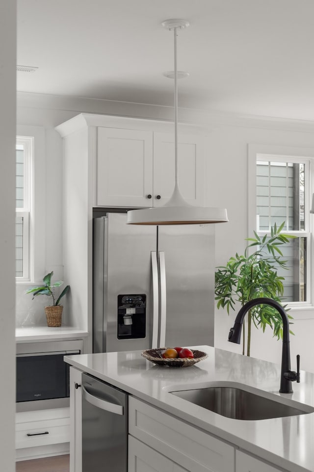 kitchen with stainless steel appliances, a sink, light countertops, and white cabinets