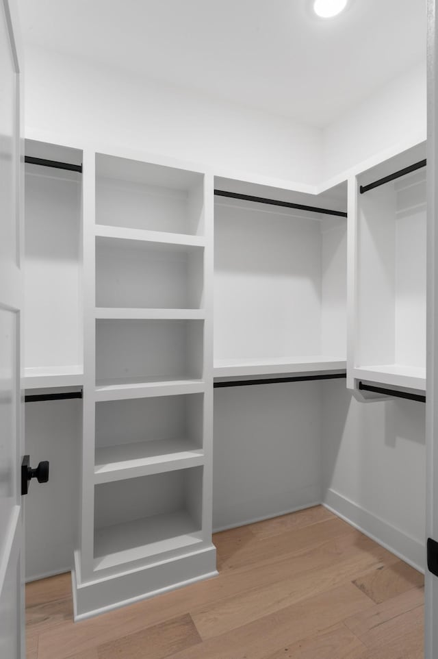 walk in closet with light wood-style floors