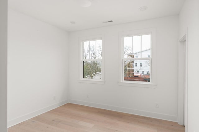 spare room featuring light wood-style floors, baseboards, and visible vents