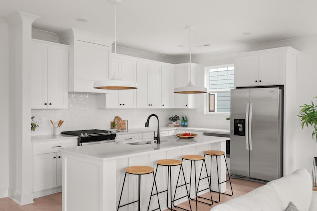 kitchen with stainless steel appliances, a sink, white cabinetry, and a kitchen breakfast bar