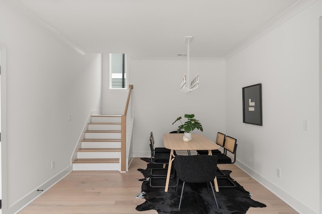 dining room featuring light wood-style floors, stairs, baseboards, and crown molding