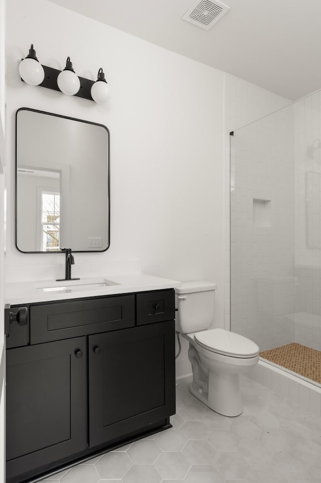 full bath featuring visible vents, toilet, a tile shower, vanity, and tile patterned floors