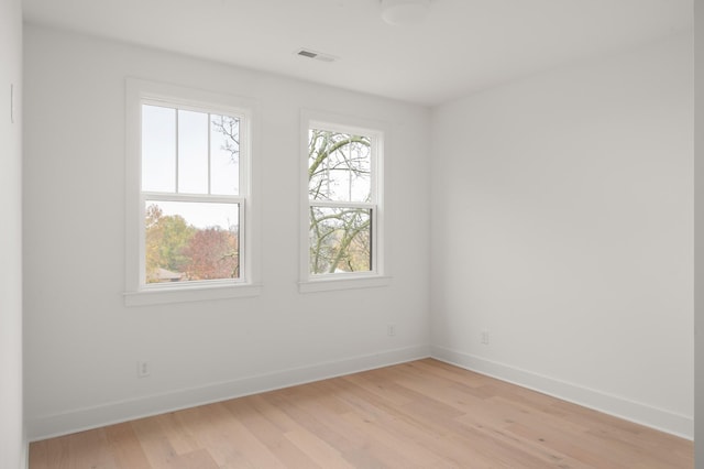 unfurnished room with light wood-type flooring, visible vents, and baseboards