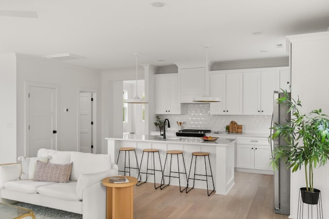 kitchen with light countertops, light wood-style flooring, backsplash, white cabinets, and a sink