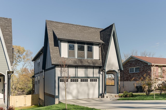 tudor home with board and batten siding, concrete driveway, a shingled roof, and a garage