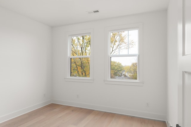 empty room featuring baseboards, visible vents, and light wood-style floors