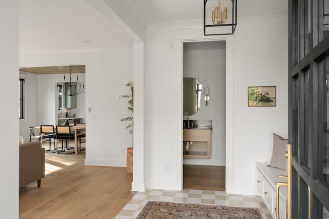 interior space featuring an inviting chandelier, baseboards, light wood finished floors, and crown molding