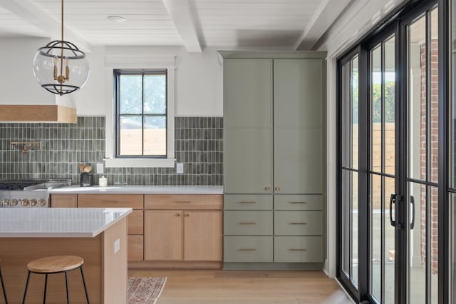 kitchen with light countertops, beamed ceiling, light wood-style flooring, and a healthy amount of sunlight