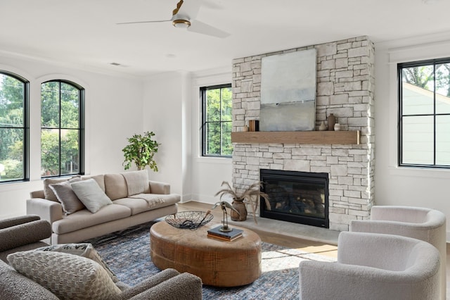 living room featuring ceiling fan, a fireplace, baseboards, and wood finished floors