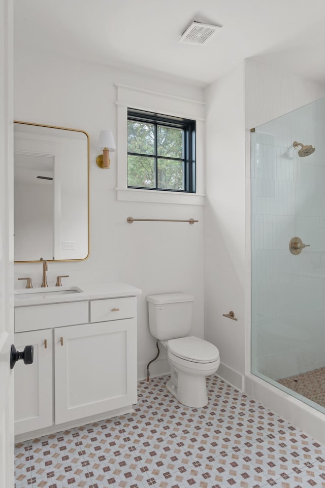 bathroom with toilet, vanity, visible vents, baseboards, and tiled shower