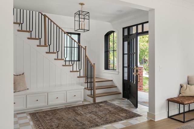 entrance foyer with light floors, stairs, baseboards, and an inviting chandelier