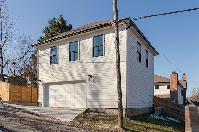 view of home's exterior with concrete driveway, central AC unit, an attached garage, and fence