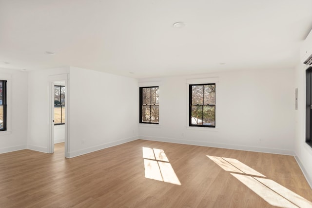 unfurnished room featuring light wood-style flooring, a wealth of natural light, and baseboards