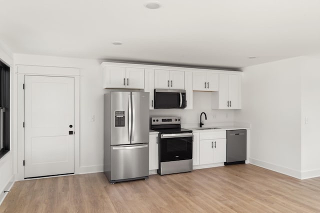 kitchen featuring white cabinets, stainless steel appliances, a sink, and light countertops