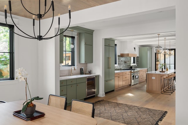 dining space with beverage cooler, a healthy amount of sunlight, a notable chandelier, and light wood-style flooring