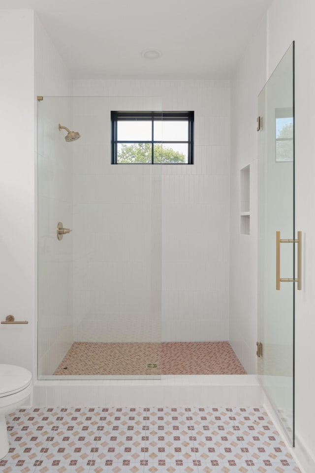 bathroom with a stall shower, tile patterned flooring, and toilet