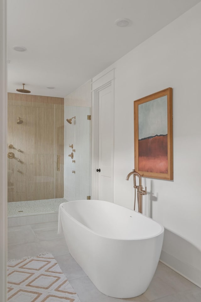 full bath featuring tile patterned flooring, a shower stall, baseboards, and a freestanding bath