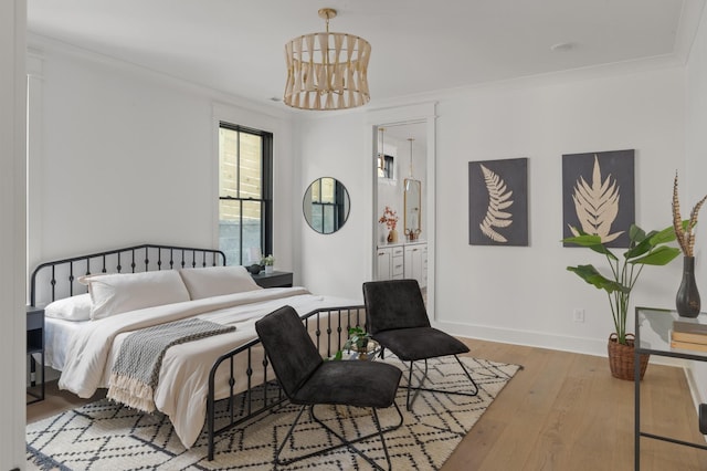 bedroom with a notable chandelier, ensuite bath, hardwood / wood-style flooring, and baseboards