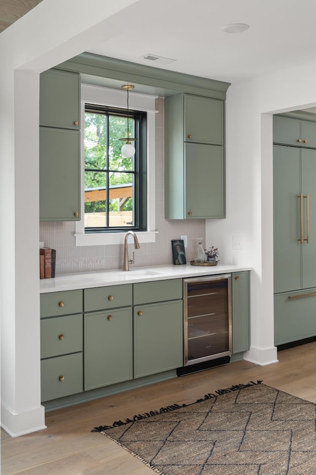 kitchen with green cabinets, wine cooler, a sink, and paneled built in fridge