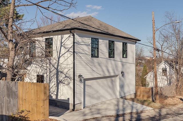 view of home's exterior featuring a garage, driveway, roof with shingles, and fence