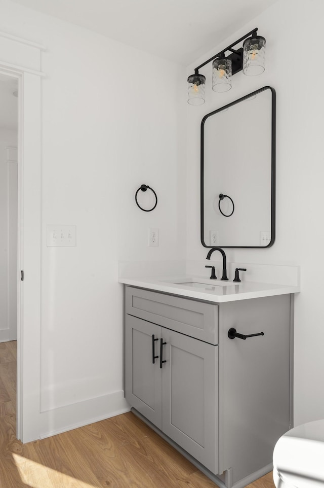 bathroom with toilet, baseboards, wood finished floors, and vanity