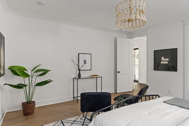 bedroom featuring baseboards, a notable chandelier, ornamental molding, and wood finished floors