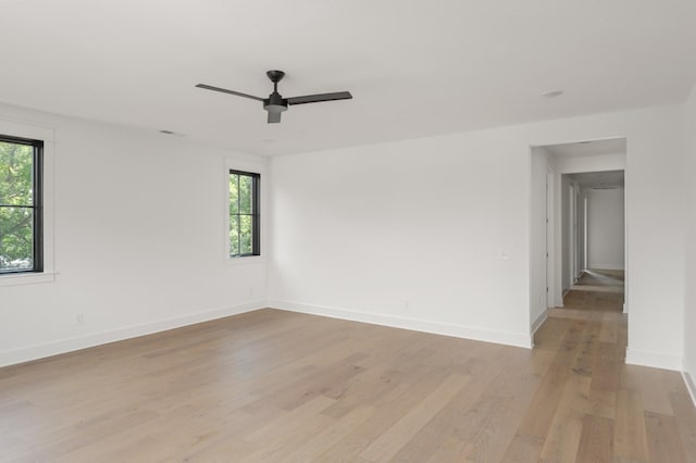 spare room with ceiling fan, light wood-style flooring, and baseboards