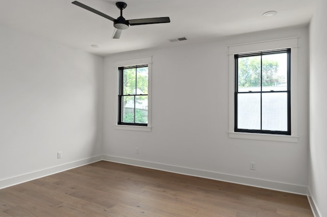 spare room featuring light wood-style flooring, visible vents, and a wealth of natural light