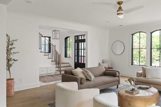 living room with stairs, baseboards, wood finished floors, and crown molding