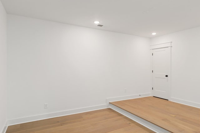 empty room with light wood-style floors, visible vents, baseboards, and recessed lighting