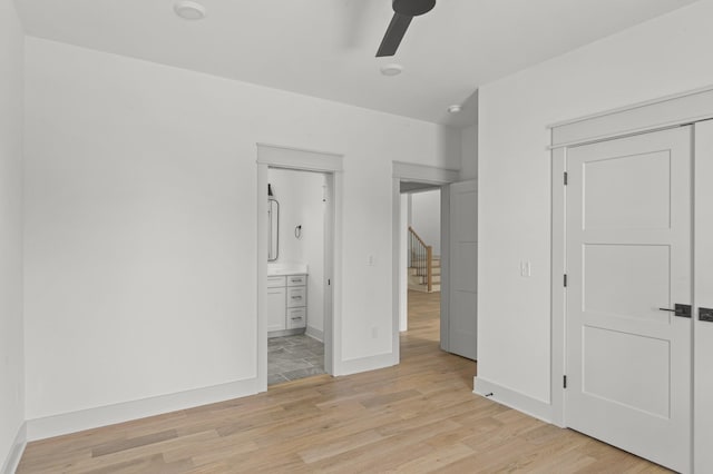 unfurnished bedroom featuring light wood finished floors, a closet, ceiling fan, ensuite bath, and baseboards